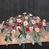 Sarggebinde in Braun und Weiß mit orangen Nelken