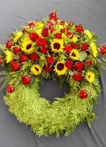 Trauerkranz mit roten Rosen und Sonnenblumen
