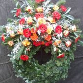 Trauerkranz mit roten Gerbera, orangenen Rosen und weißem Ginster