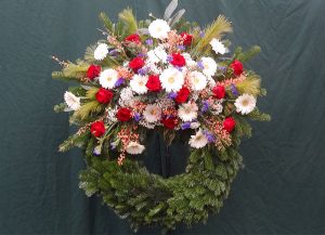 Trauerkranz mit weißen Gerbera, roten Rosen und blauen Perlhyazinthen