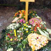 Grab nach der Beisetzung, abgedeckt mit Efeuranken und dekoriert mit Trauergestecken aus der Feierhalle